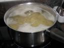 Les pommes de terre épluchées et coupées en rondelles blanchissent dans l’eau bouillante.